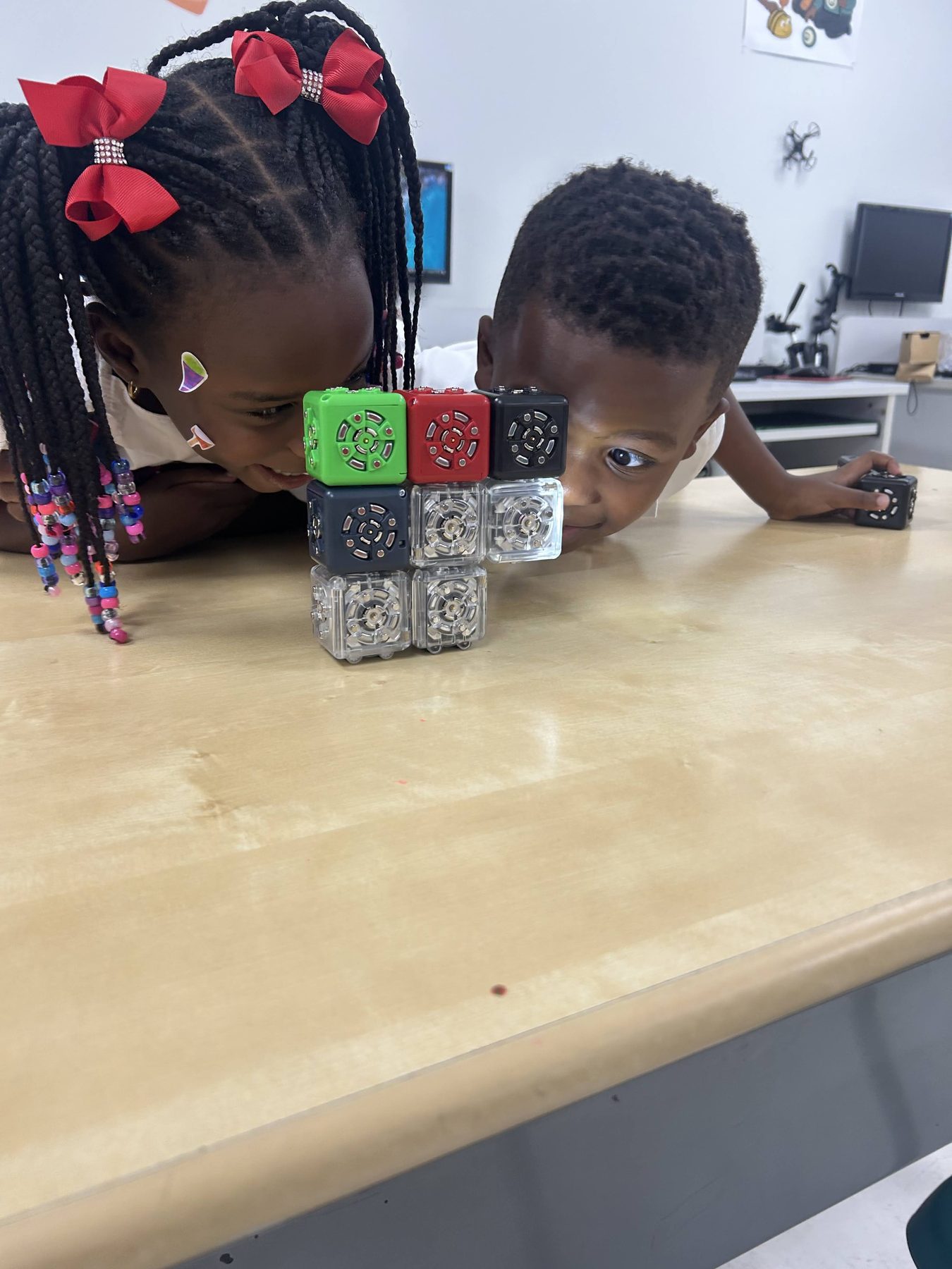 Two young Imani students closely examining a structure built with robotic Cubelets.