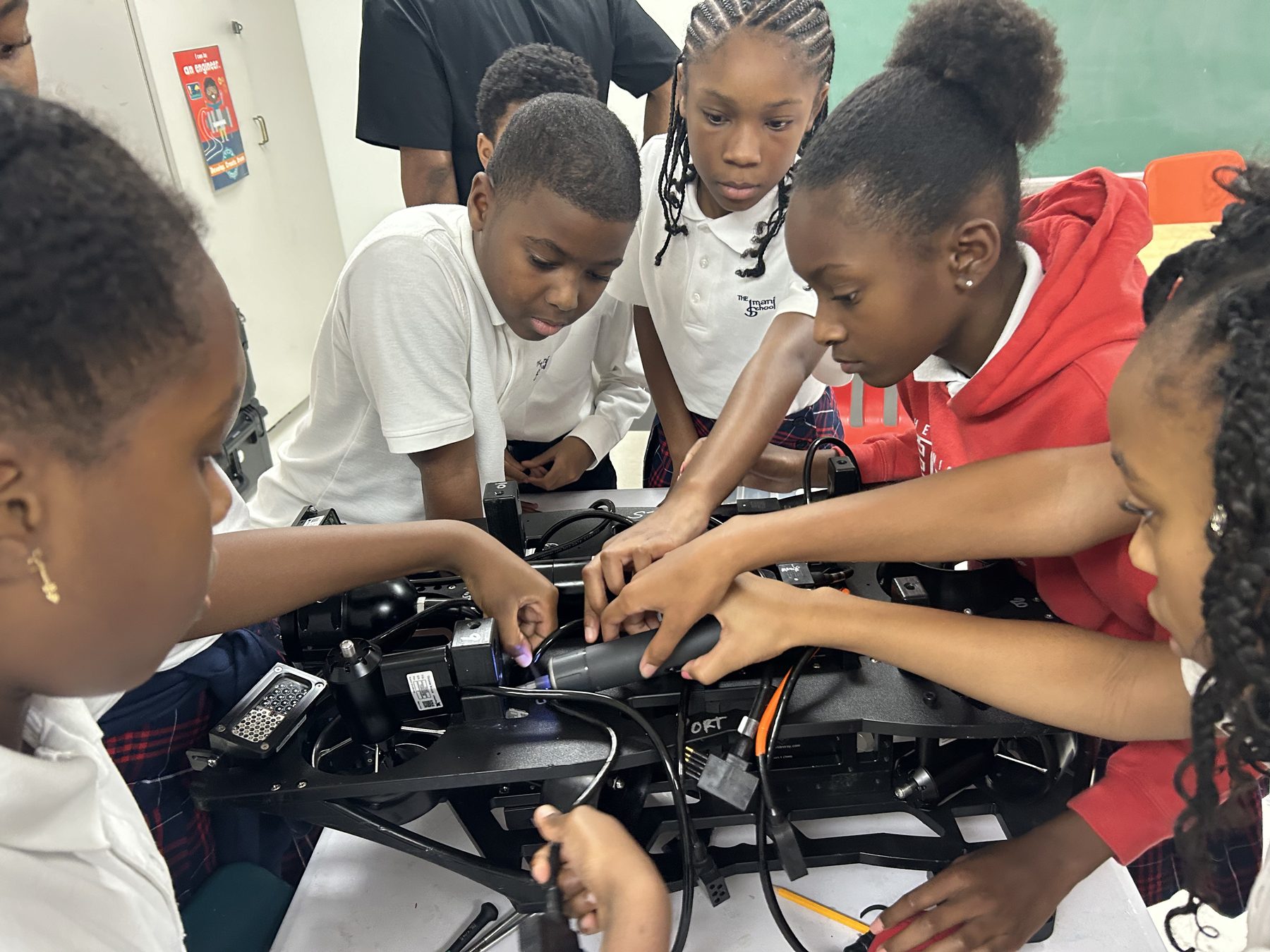 Imani students working together on a large robotics assembly.