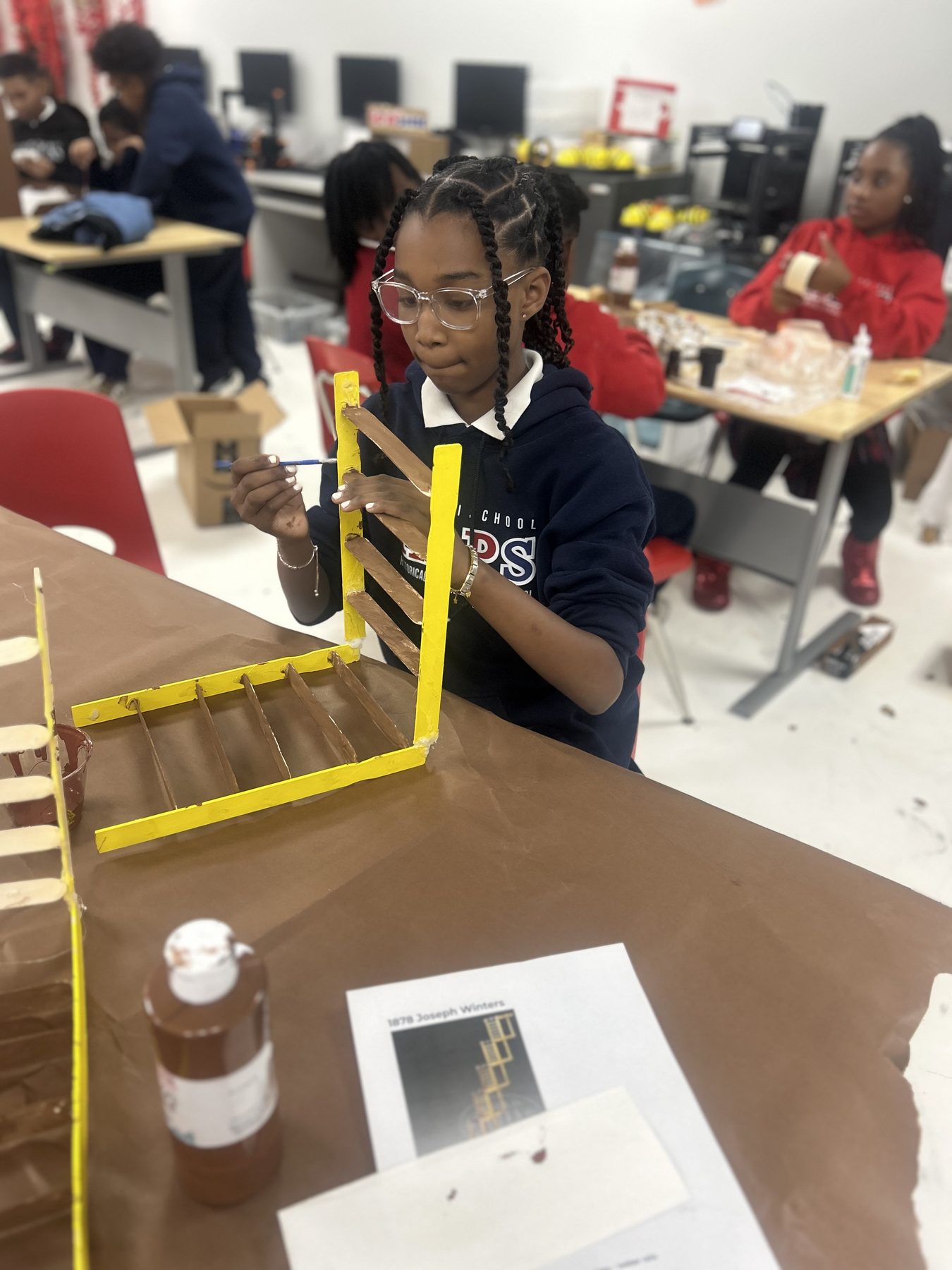 Imani student painting an engineering model inspired by inventor Joseph Winters.