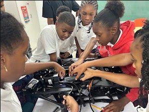 Imani students gathered around technical equipment during a STEM activity.